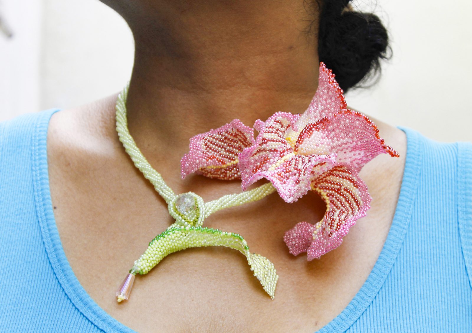 A pink beaded orchid on a green beaded stem worn at the neck