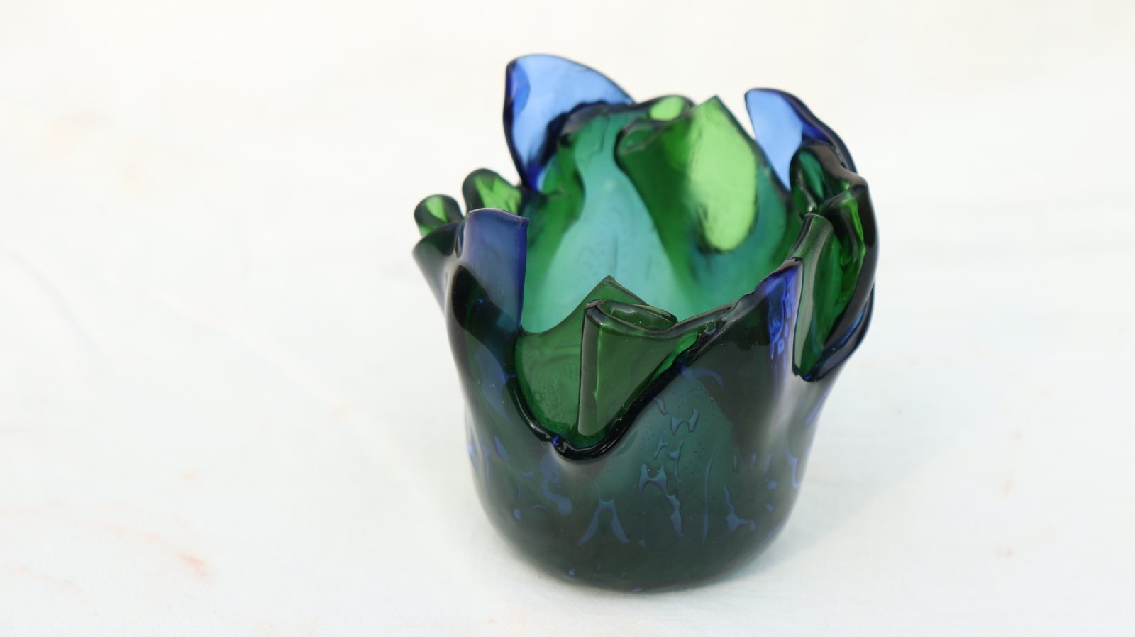 A small vessel in blue and green glass with petal-like rim