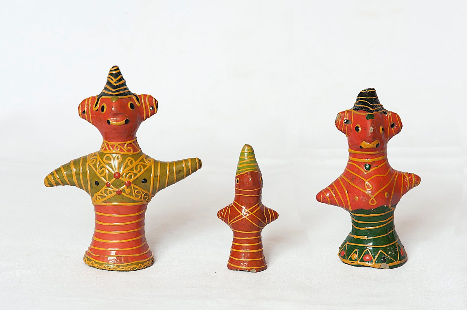 Three small painted lac dolls in orange, green and yellow