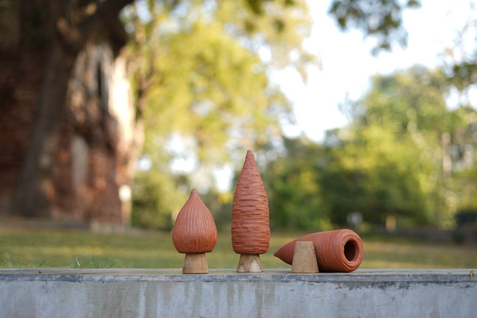Three terracotta cones of different sizes standing on a ledge in sunlight
