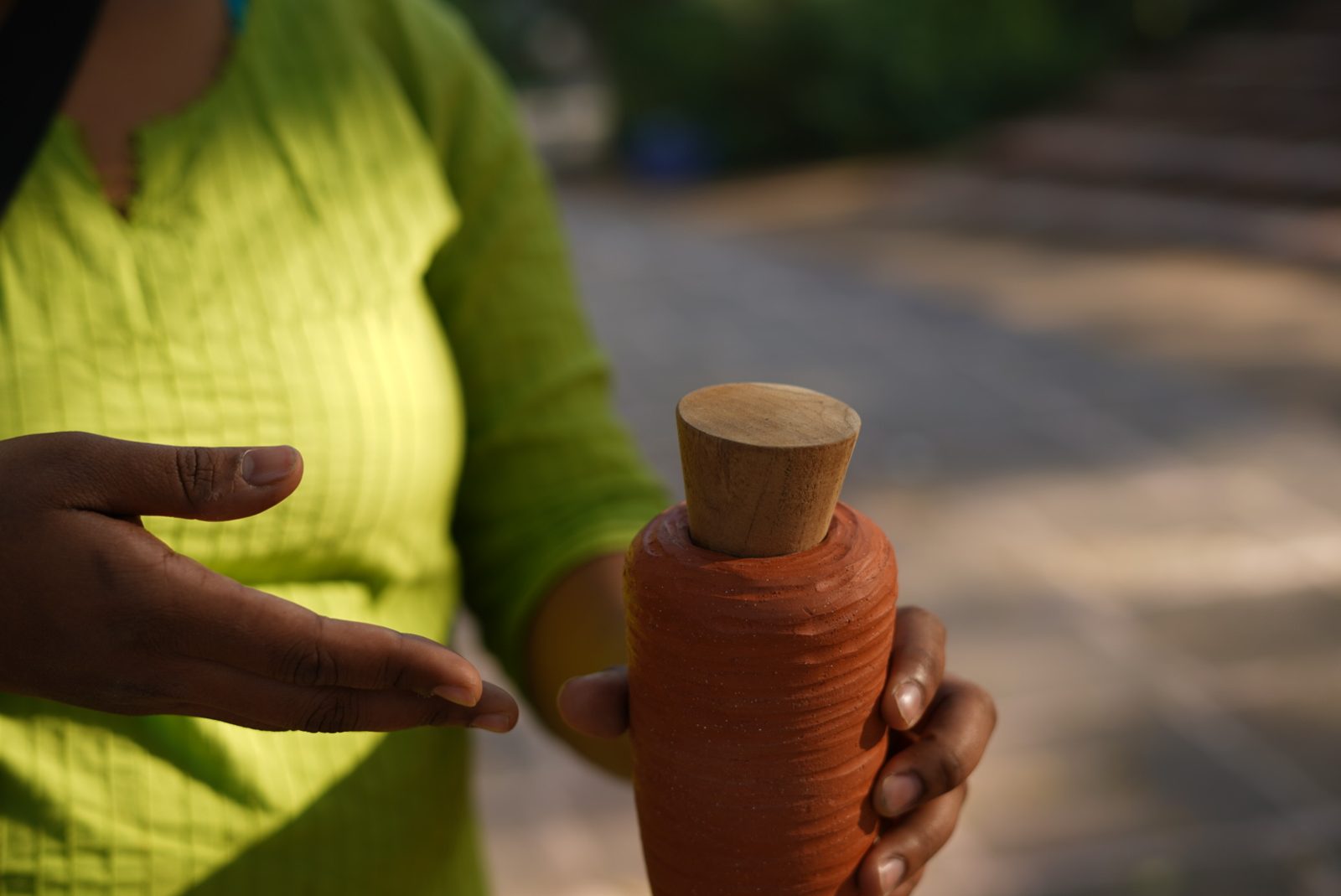 A hand holding a terracotta cone with its wooden stopper