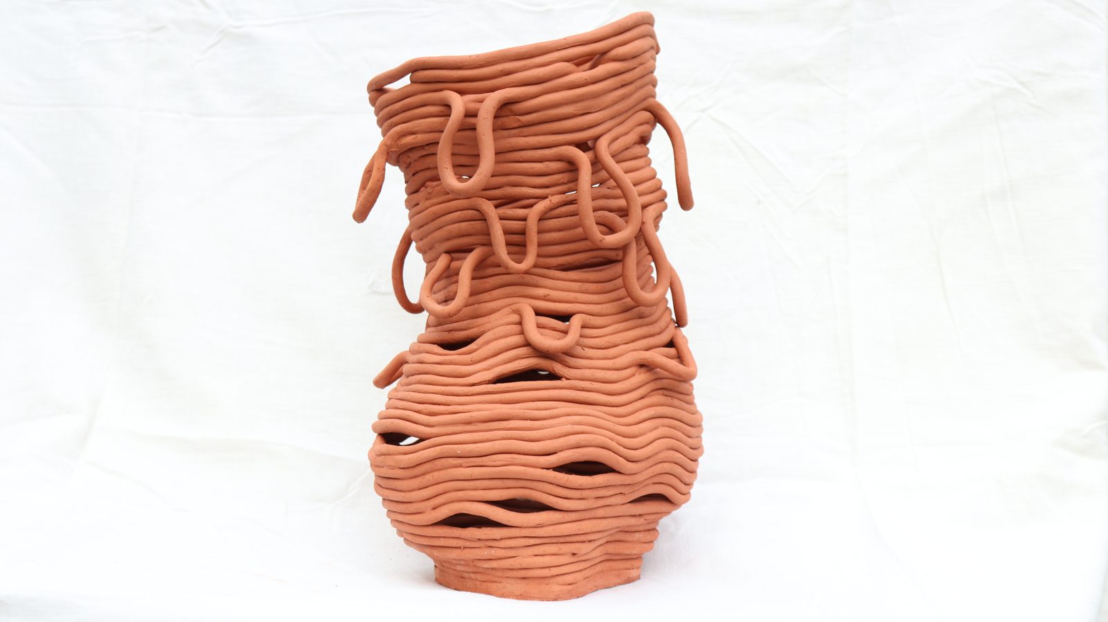A tall vessel built from loose terracotta coils